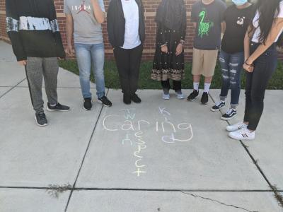 students feet with the word Caring and other words written in chalk